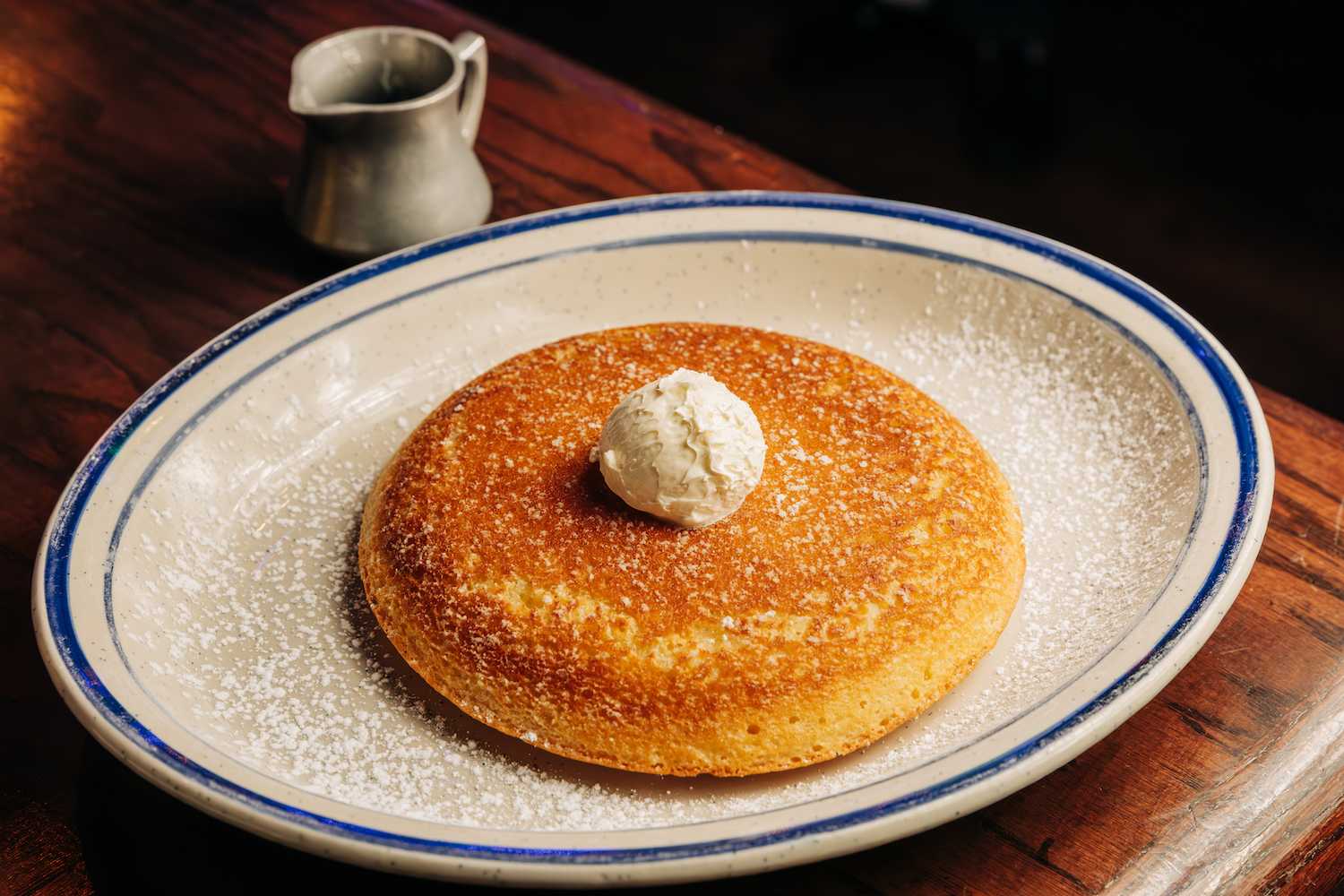 Massive pancake topped with butter and a side of syrup
