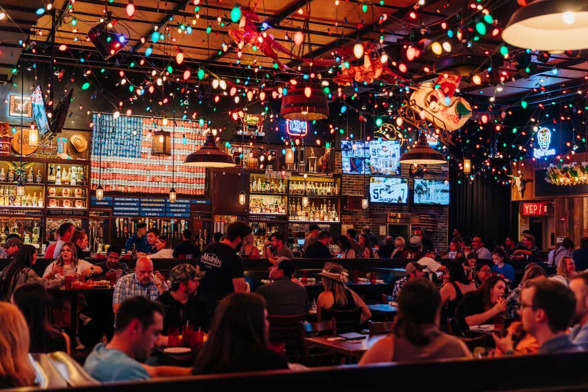 Wide photo of Bub City Rosemont's dining room, filled with Christmas lights and an American flag made of beer cans
